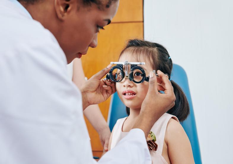 Optometrist detecting myopia in young girl